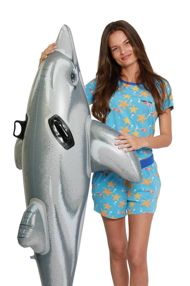 Vrouw draagt een blauwe shortama, ze staat met opblaasdolfijn voor in het water