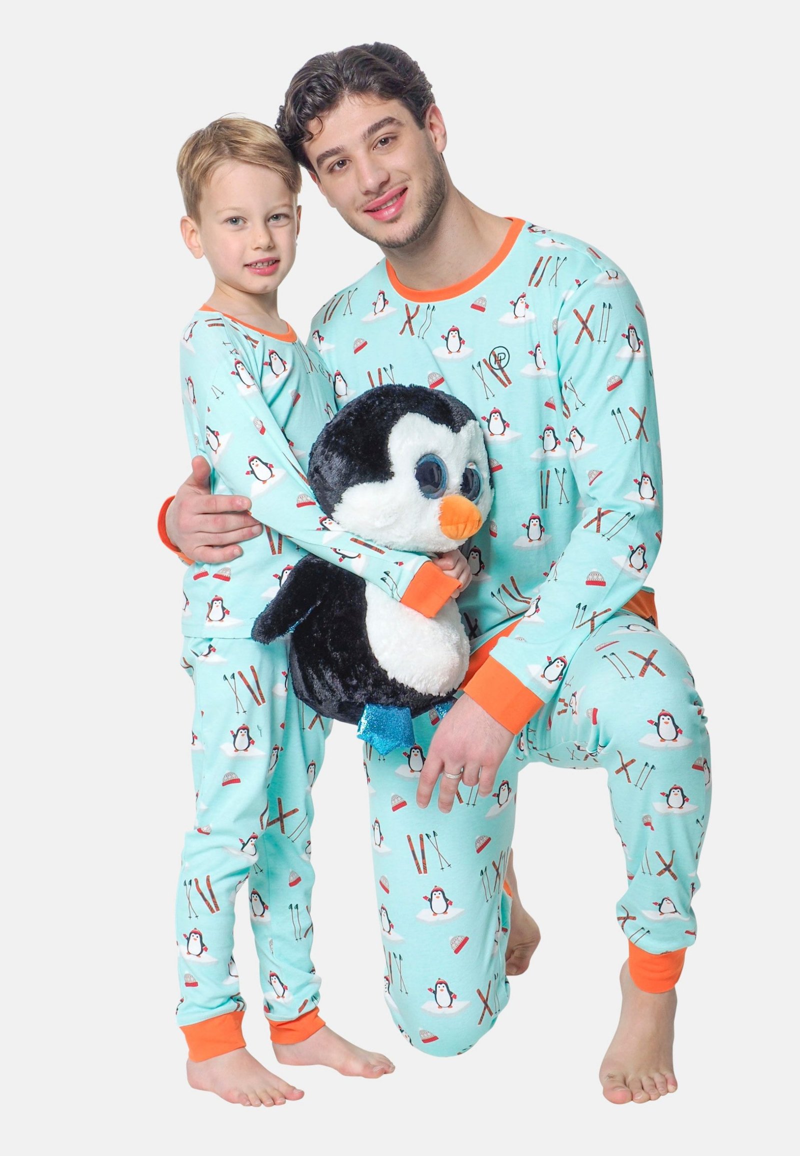 Vader en zoon samen in dezelfde twinning pyjama met een leuke pinguin knuffel om mee te slapen