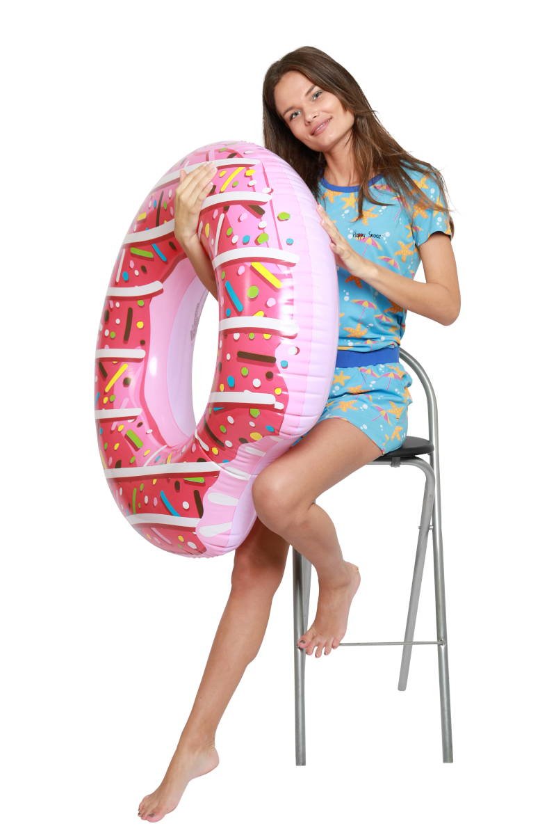 Dame met roze zwemband en blauwe shortama dames met zeesterren en parasols, zittend op een kruk