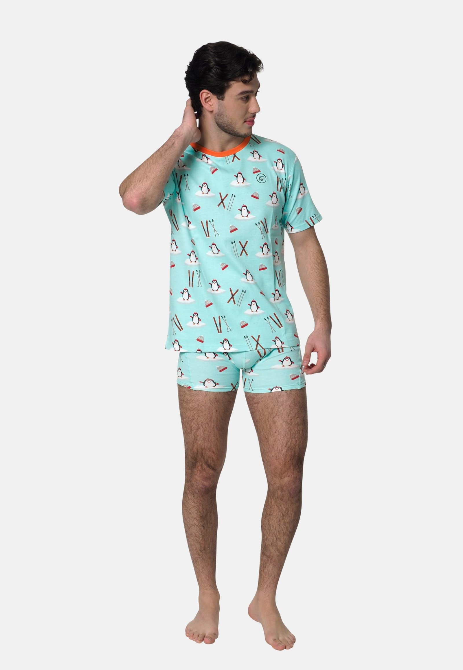 Man heeft hand in de nek en draagt een blauwe heren shortama met pinguin, skies en een oranje elastische band