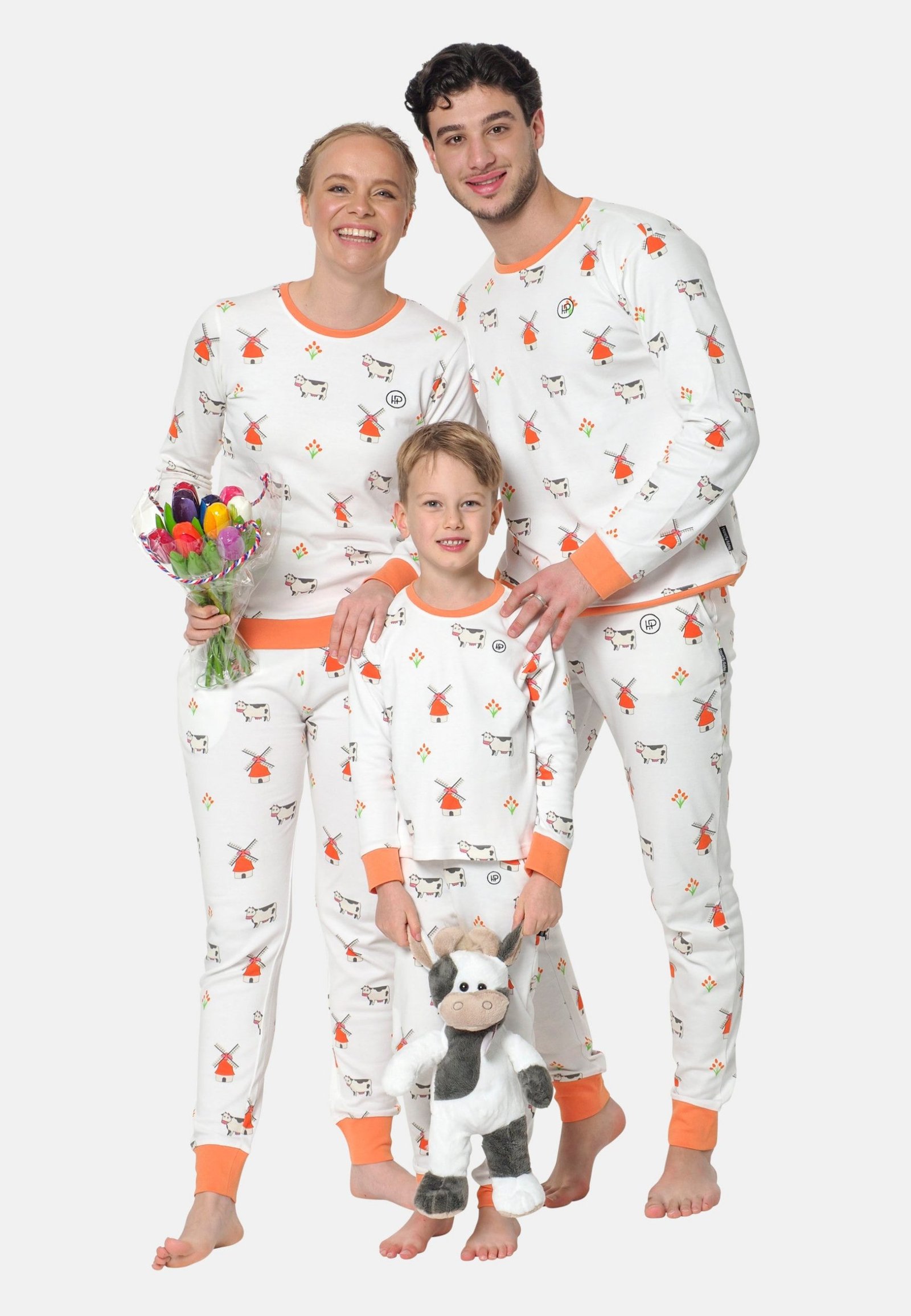 Een vrolijk gezin met een twinning pyjama aan, een witte pyjama met oranje, koeien, tulpen en molens