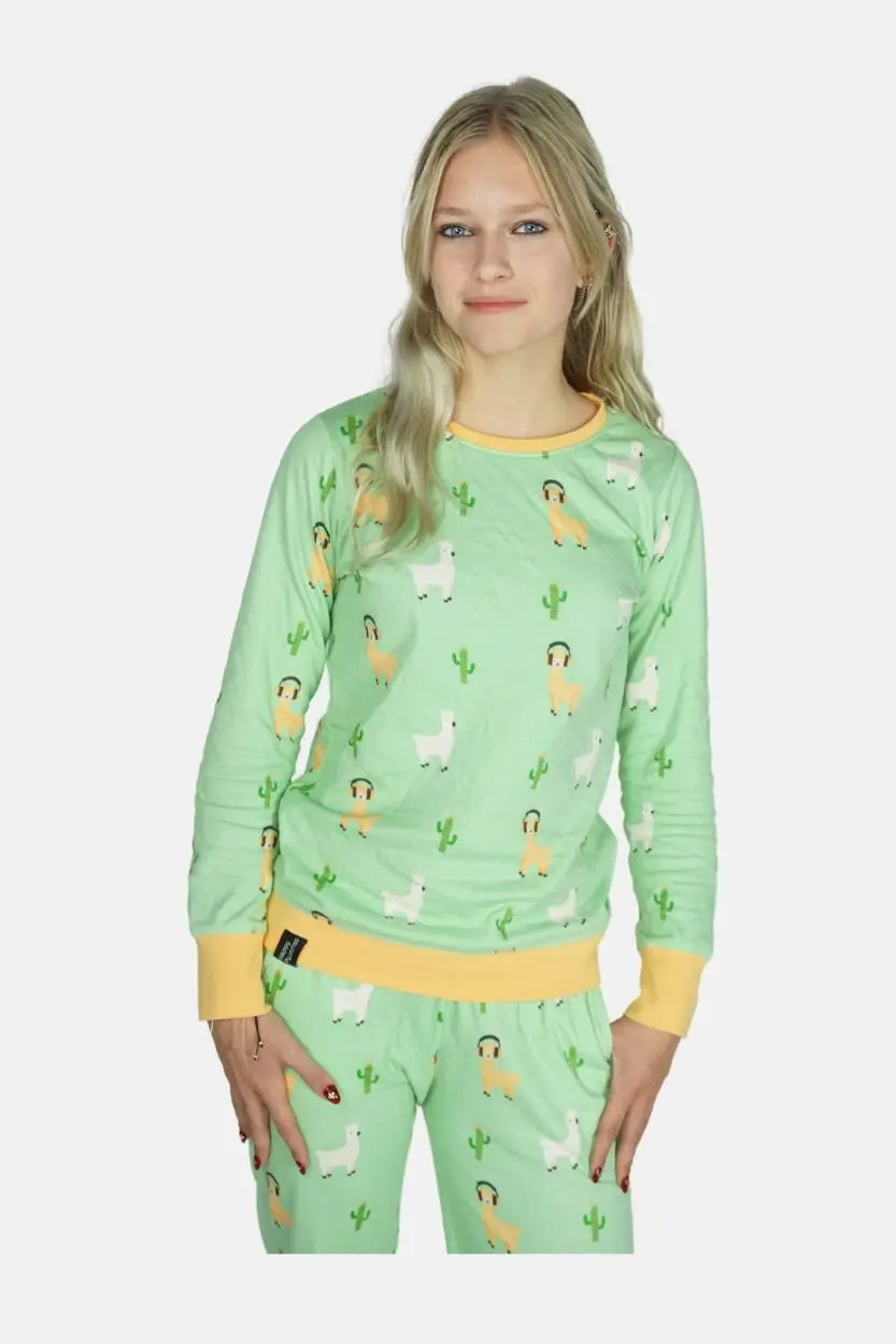 Blond jong model lacht in de camera en een lichtgroene grappige alpaca pyjama. Bordes zijn lichtoranje en van elastiek met ribstof.