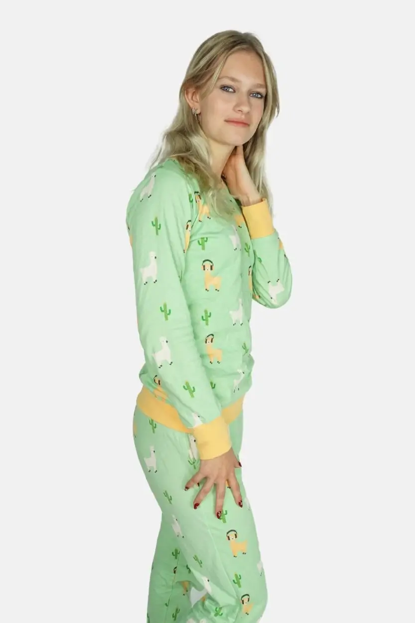 Alpaca pyjama met cactussen en alpaca's met een hoofdtelefoon. Model staat met haar zij naar de camera met een hand op één been.
