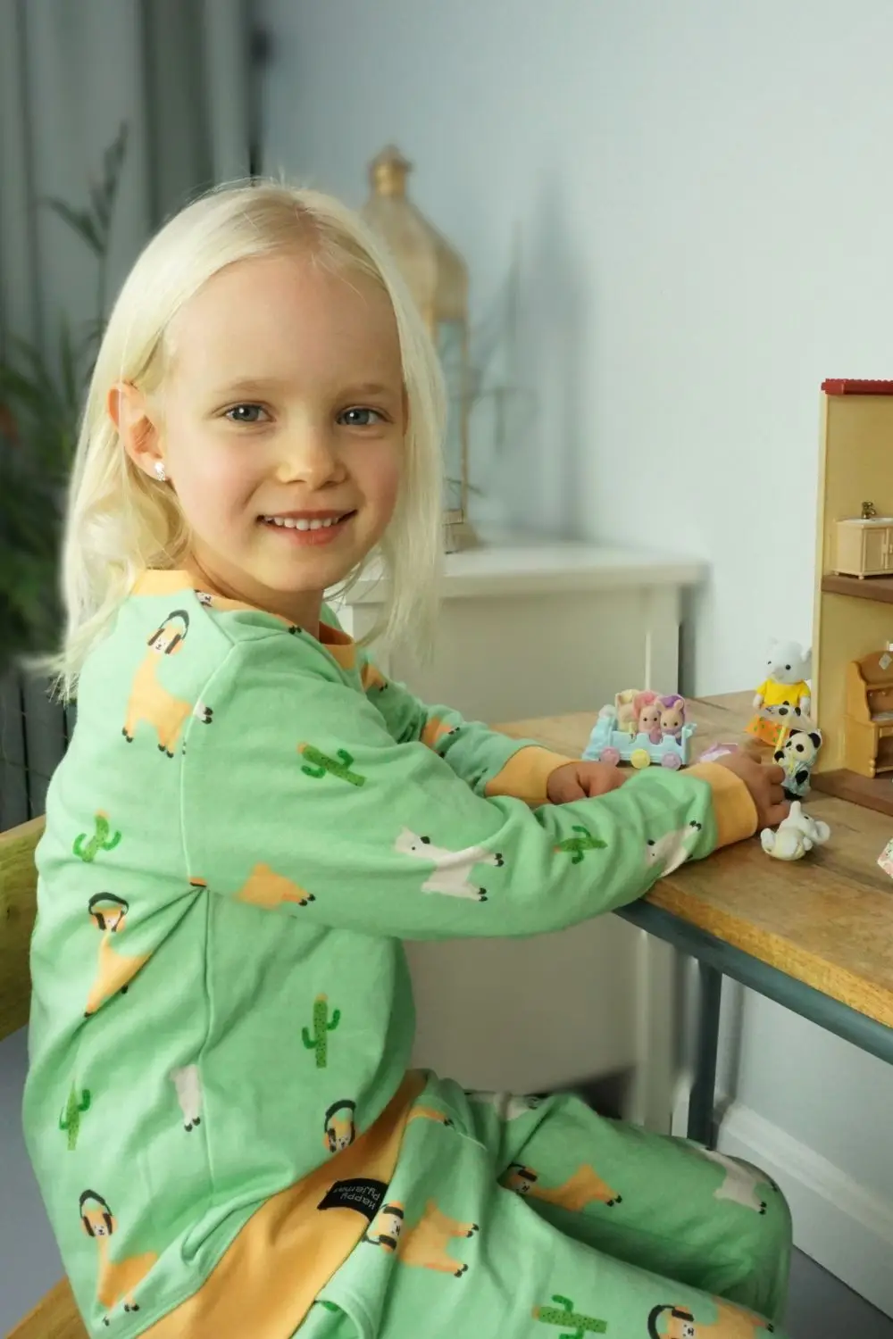 Meisje aan een tafel aan het spelen in een alpaca kinderpyjama.